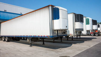 Refrigerated truck trailers lined up at a distribution warehouse.